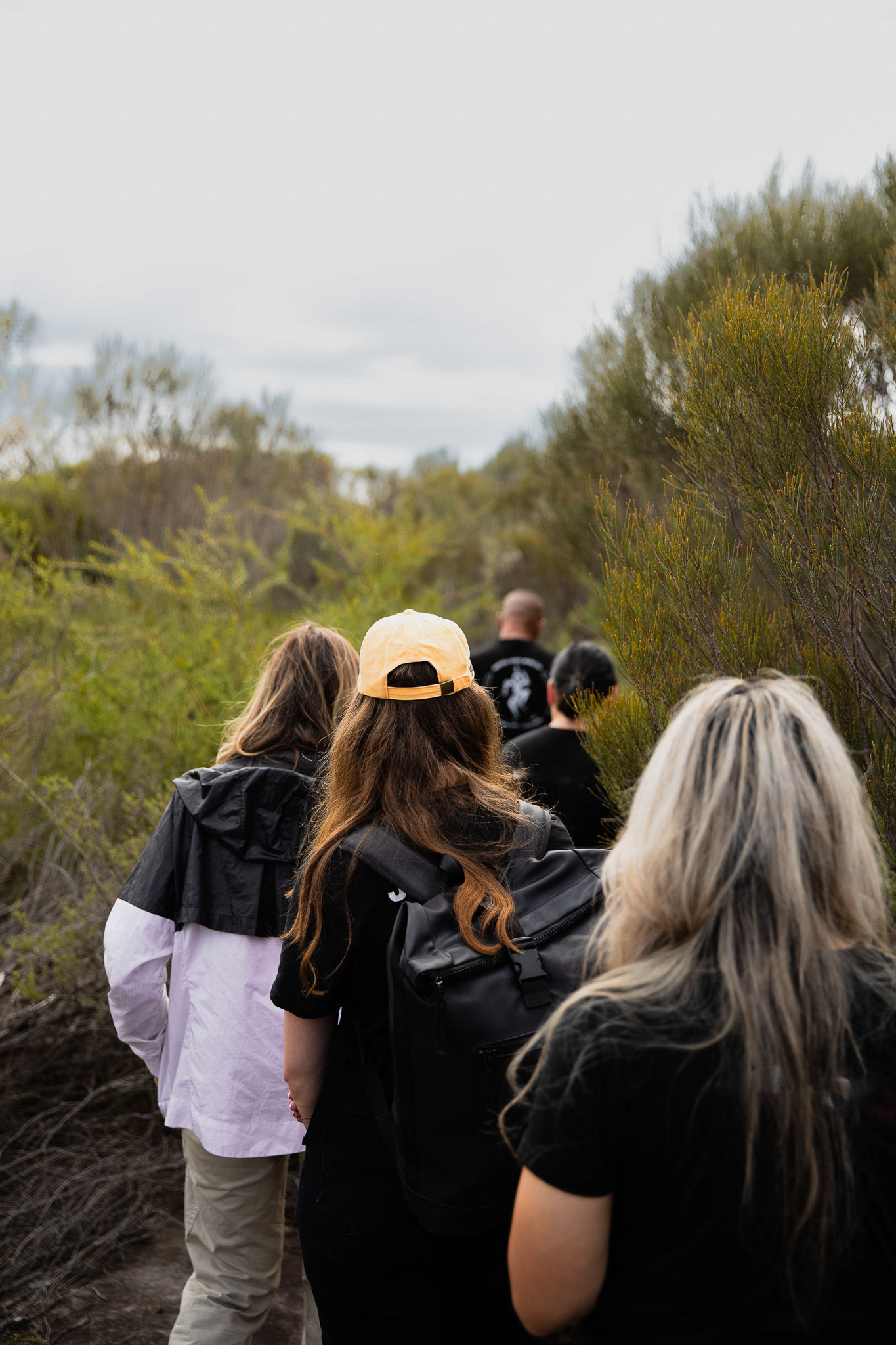 Guests following a guide along a narrow bushland walking track.