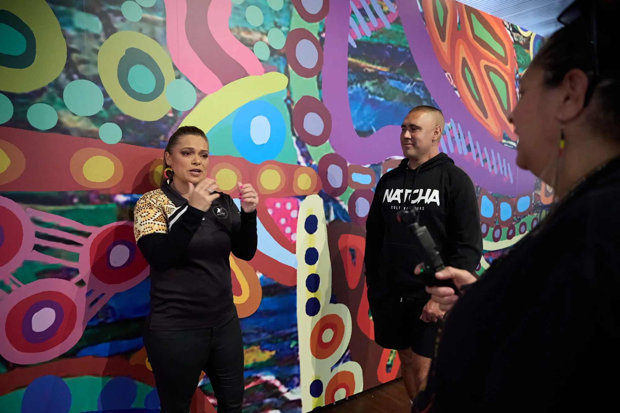 Guides speaking with a guest beside a colourful public artwork.